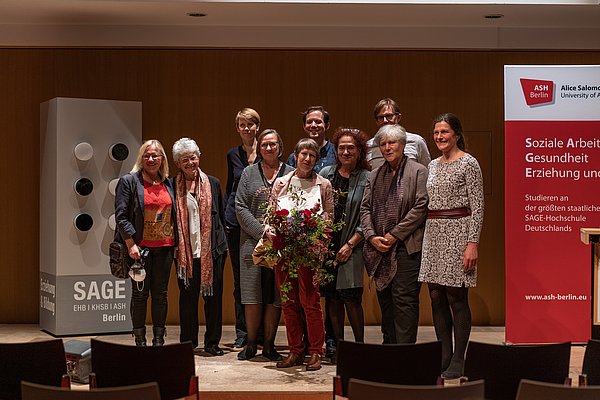 Gruppenfoto Preisträgerin Adrienne Chambon mit weiteren Personen auf der Bühne im Audimax der ASH Berlin