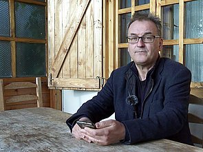 Jan Koneffke an einem Tisch vor einem Haus, in der Hand sein Handy
