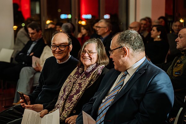 Anna Csongor sitzt im Audimax neben ihrem Mann und Bruder