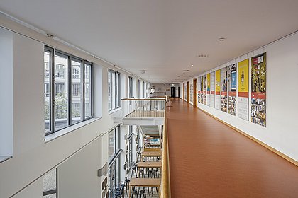 Blick über einen Flur der ASH Berlin, an der Wand hängen bunte Poster